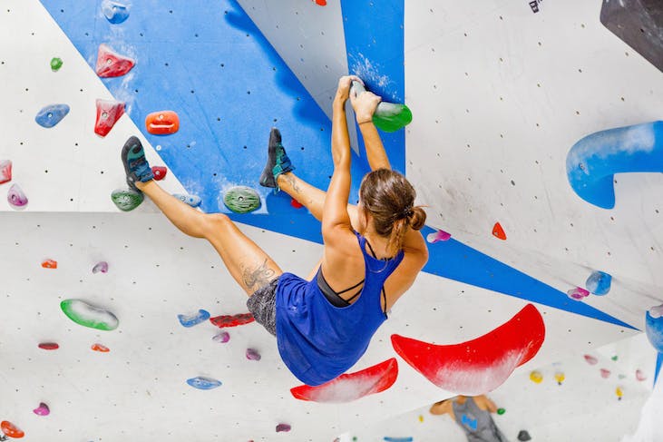 a woman rock climbing at an indoor facility
